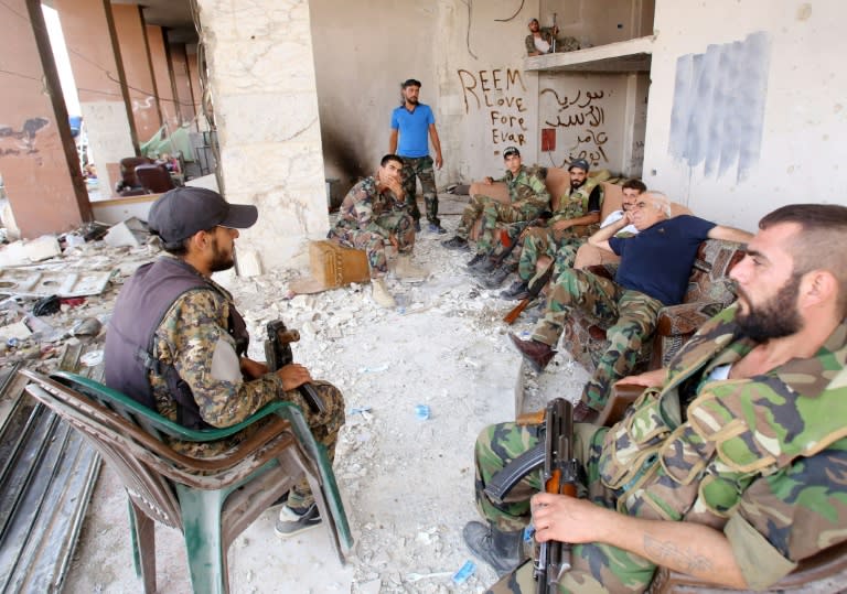 Syrian army soldiers gather at the entrance of a damaged building in the besieged town of Daraya on August 26, 2016