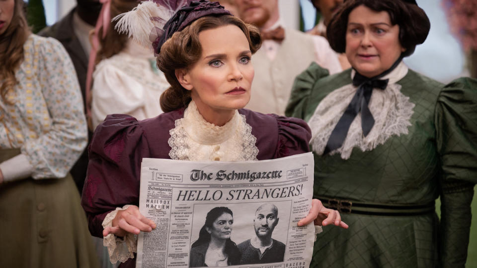 A woman angrily holds a newspaper front page open