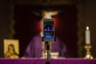 Catholic priest Catholic priest Jesus Higueras from the Santa Maria de Cana parish is seen on a smartphone during a live video streamed mass in Pozuelo de Alarcon, outskirts Madrid, Spain, Sunday, March 15, 2020. Pope Francis has praised people for their continuing efforts to help vulnerable communities, including the poor and the homeless, amid the coronavirus pandemic. The vast majority of people recover from the COVID-19. According to the World Health Organization, most people recover in about two to six weeks, depending on the severity of the illness. (AP Photo/Bernat Armangue)