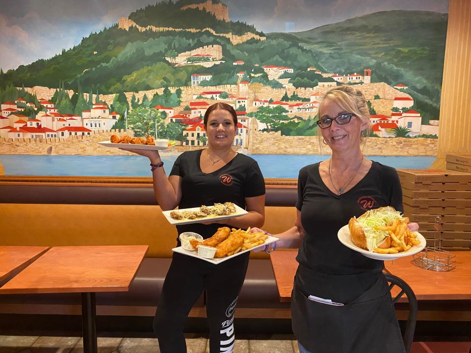 Bar manager Amanda Hill, left, and waitress Kelly Cavaro hold plates of delicious options offered at New Weir Pizza in Taunton, seen here on Monday, Oct. 18, 2021.