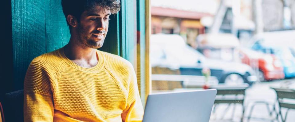 Smiling hipster guy applying for debt consolidation loan online