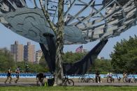 Runners and cyclists wear protective masks during the coronavirus pandemic as they pass the Unisphere, Tuesday, May 26, 2020, in the Queens borough of New York. (AP Photo/Frank Franklin II)