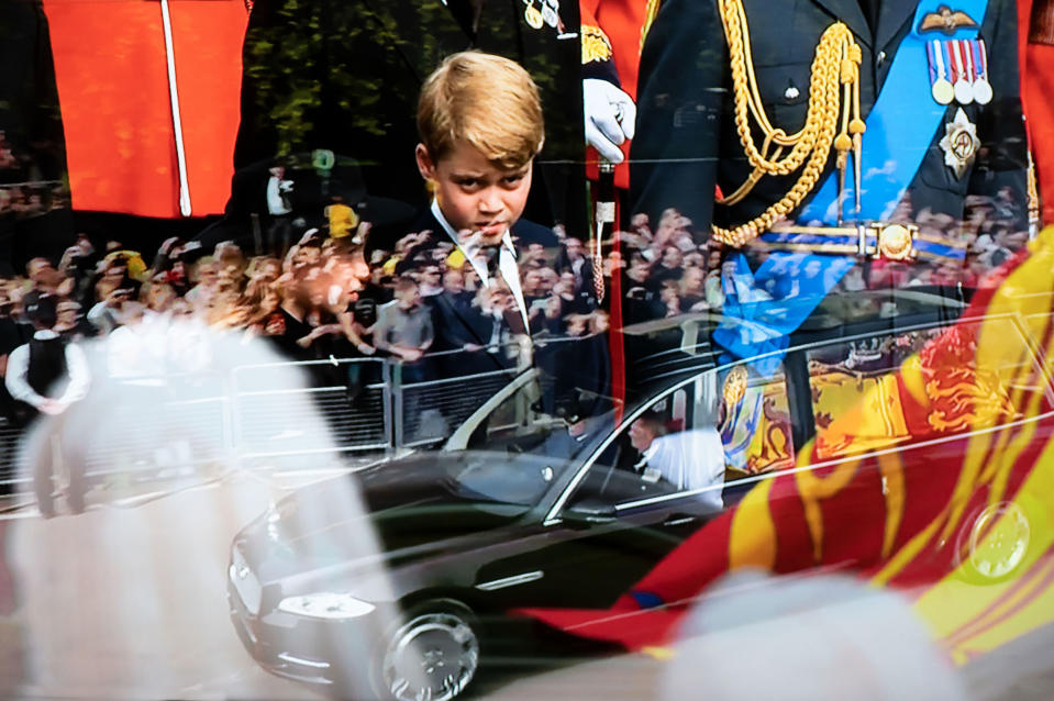 Photographed from a television broadcast, Queen Elizabeth's coffin in the State Hearse is driven to Windsor past crowds lining the road with Prince George, second in line to the throne, in the background.<span class="copyright">Ian Berry—Magnum Photos</span>