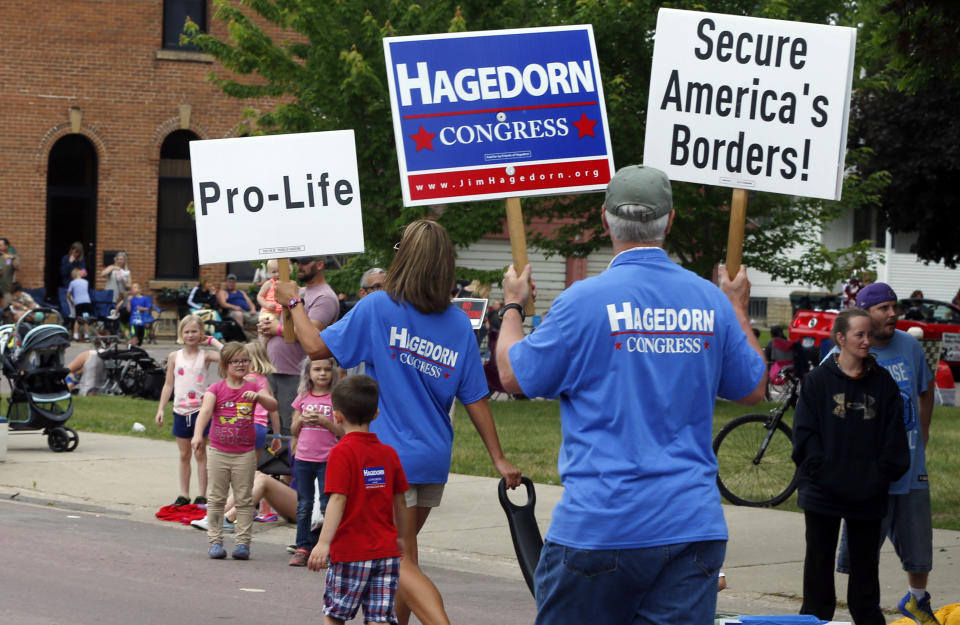 In this June 10, 2018 photo, volunteers for Minnesota 1st District congressional candidate Jim Hagedorn carry signs during a parade in Waterville, Minn. Waterville's 54th annual Bullhead Days parade included Republican Hagedorn and Democrat Dan Feehan, candidates who came to shake as many hands as they could in the open seat race which promises to be one of the most closely watched races in the country. (AP Photo/Jim Mone)