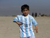 Five year-old Murtaza Ahmadi, an Afghan Lionel Messi fan, wears a shirt signed by Barcelona star Lionel Messi, as he plays football at the open area in Kabul, Afghanistan February 26, 2016. REUTERS/Omar Sobhani