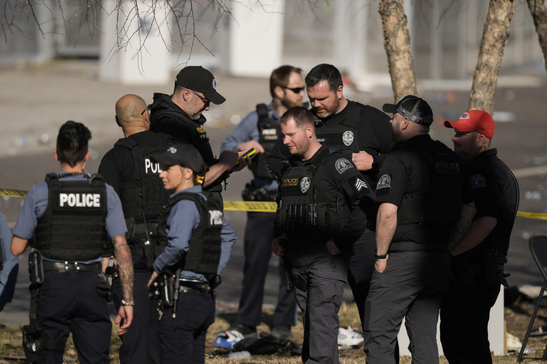 Law enforcement officers look around the scene after the shooting.