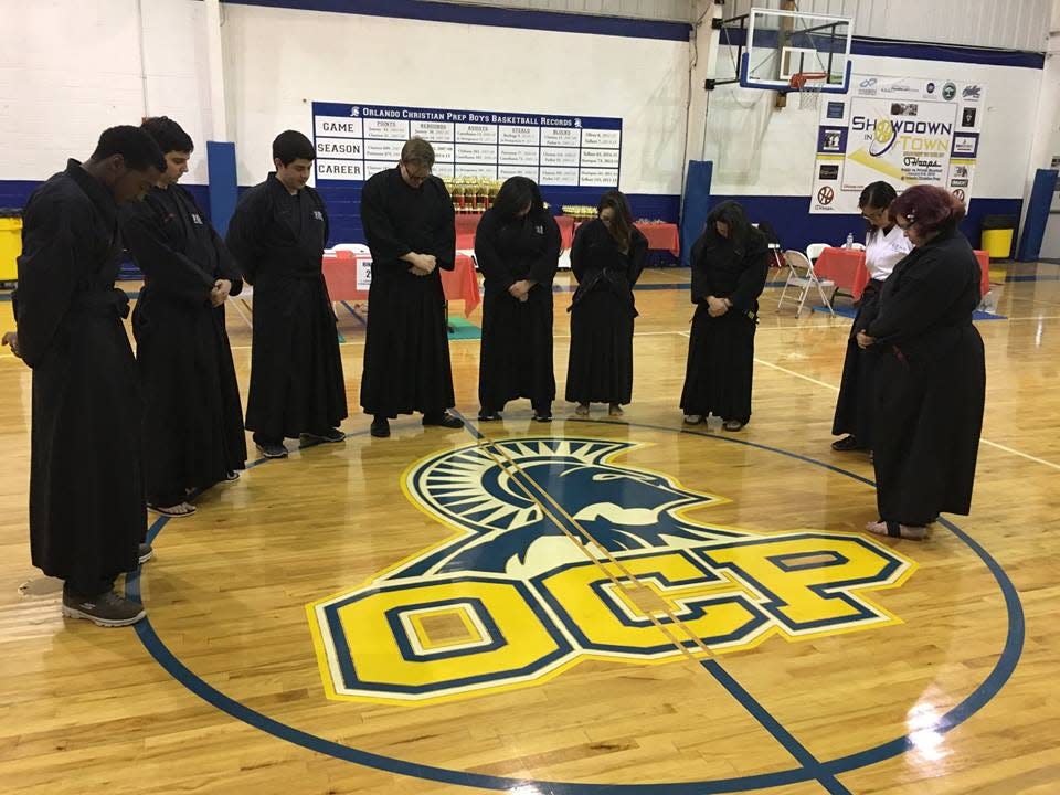 In Orlando, Fla., youth members of Black Belts for Christ gather for a group prayer before the start of an organization-sponsored tournament in 2016. Founder Joe Morejon, who incorporates Bible scripture into his dojo teachings, said many of his students have become distanced from traditional church teachings but still seek fellowship and connection. "They're looking for a more immersive experience," he said.