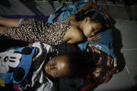 In this Sept. 3, 2018 photo, Venezuelan Sandra Cadiz and her 10-year-old daughter Angelis, lie on the floor of a gas station where they spent the night at a place known only as "Kilometer 17" in Santander state, Colombia, on their journey to Peru. All through the night it rained and thundered. Water blew onto their blankets, forcing them to repeatedly get up and move to whichever edge of the gas station had managed to stay dry. (AP Photo/Ariana Cubillos)