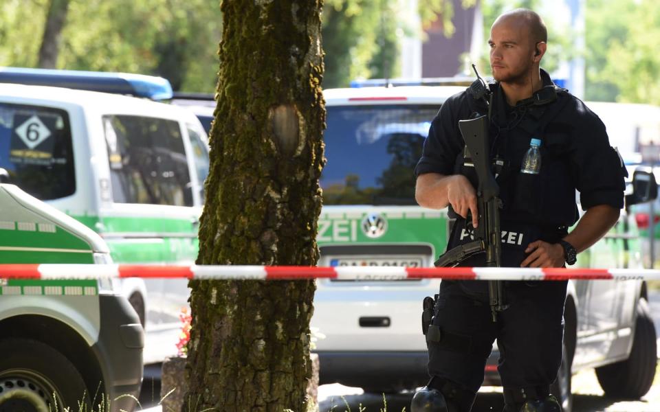 A police officer secures the area around a commuter rail station in Unterfoehring near Munich - Credit: CHRISTOF STACHE/AFP