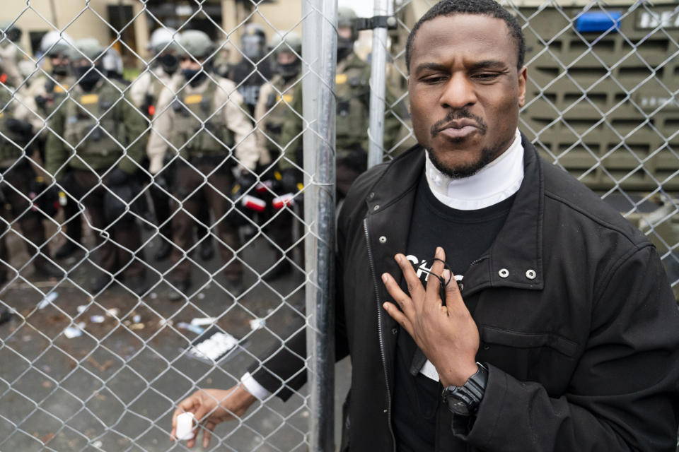 Michael Odiari attempts to calm demonstrators at a perimeter security fence as authorities prepare to engage during a protest decrying the shooting death of Daunte Wright outside the Brooklyn Center Police Department, Wednesday, April 14, 2021, in Brooklyn Center, Minn. (AP Photo/John Minchillo)