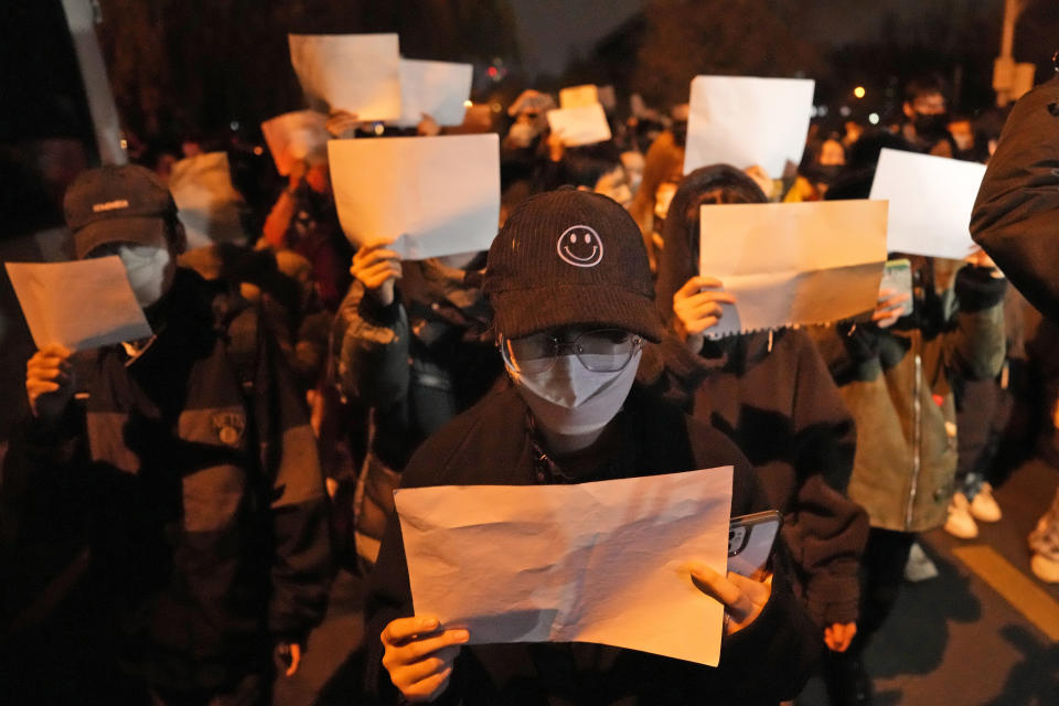 FILE - Protesters hold up blank papers and chant slogans as they march in protest strict anti-virus measures in Beijing, Nov. 27, 2022. China's sudden reopening after two years holding to a "zero-COVID" strategy left older people vulnerable and hospitals and pharmacies unprepared during the season when the virus spreads most easily, leading to many avoidable deaths, The Associated Press has found. (AP Photo/Ng Han Guan, File)