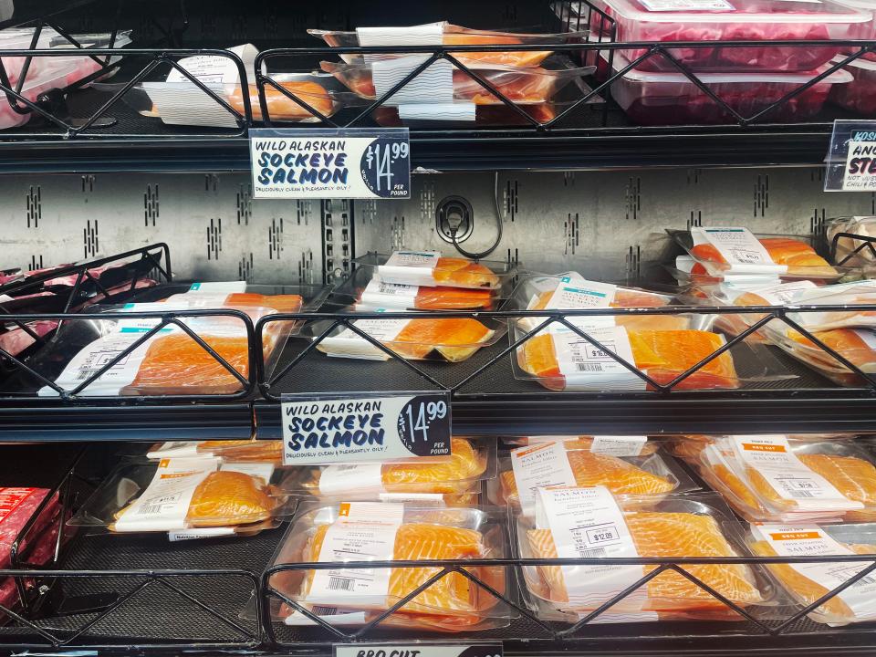 Clear packages of wild Alaskan sockeye salmon on black shelves in meat section at