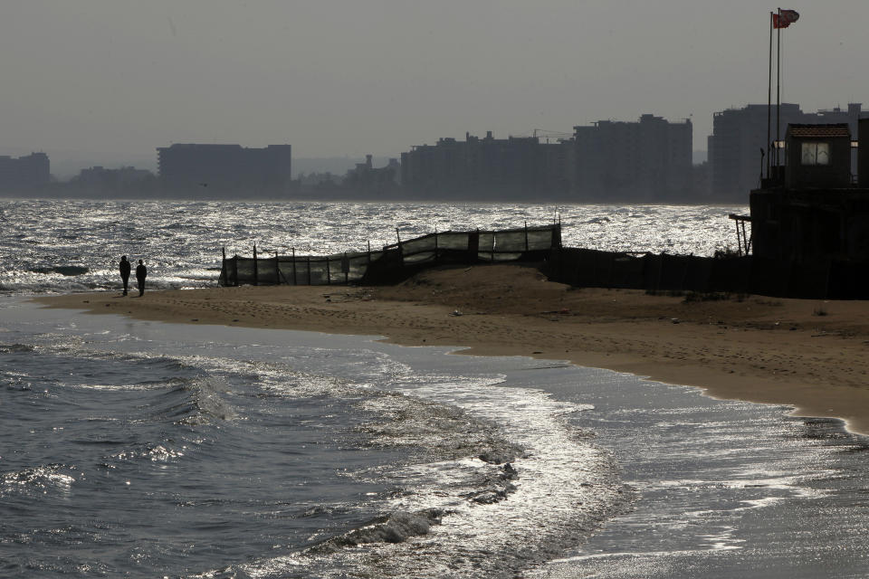 FILE - In this Friday, Jan. 17, 2014 file photo, men walk at the beach by a military guard post, right, in front of deserted hotels in an area used by the Turkish military in the Turkish occupied area in the abandoned coastal city of Varosha, Famagusta, southeast Cyprus. The man who hopes to be the next leader of the breakaway Turkish state in northern Cyprus, Ersin Tatar says ongoing tensions over drilling for oil and gas would fade if Greek Cypriots drop their objections and agree to divvy up the country’s territorial waters and drilling rights. (AP Photo/Petros Karadjias, File)