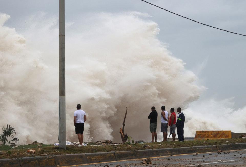 People stand in front of waves crashing against the shore as Hurricane Beryl moves south of the island, in Santo Domingo, Dominican Republic, on July 2, 2024.<span class="copyright">Erika Santelices—Reuters</span>