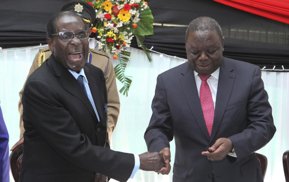 FILE - In this Wednesday, May 22, 2013 file photo Zimbabwean President Robert Mugabe, left, shakes hands with Prime Minister Morgan Tsvangirai after he signed the new constitution into law at State house in Harare. On Friday, Sept. 6, 2019, Zimbabwe President Emmerson Mnangagwa said his predecessor Robert Mugabe, age 95, has died. (AP Photo/Tsvangirayi Mukwazhi, File)