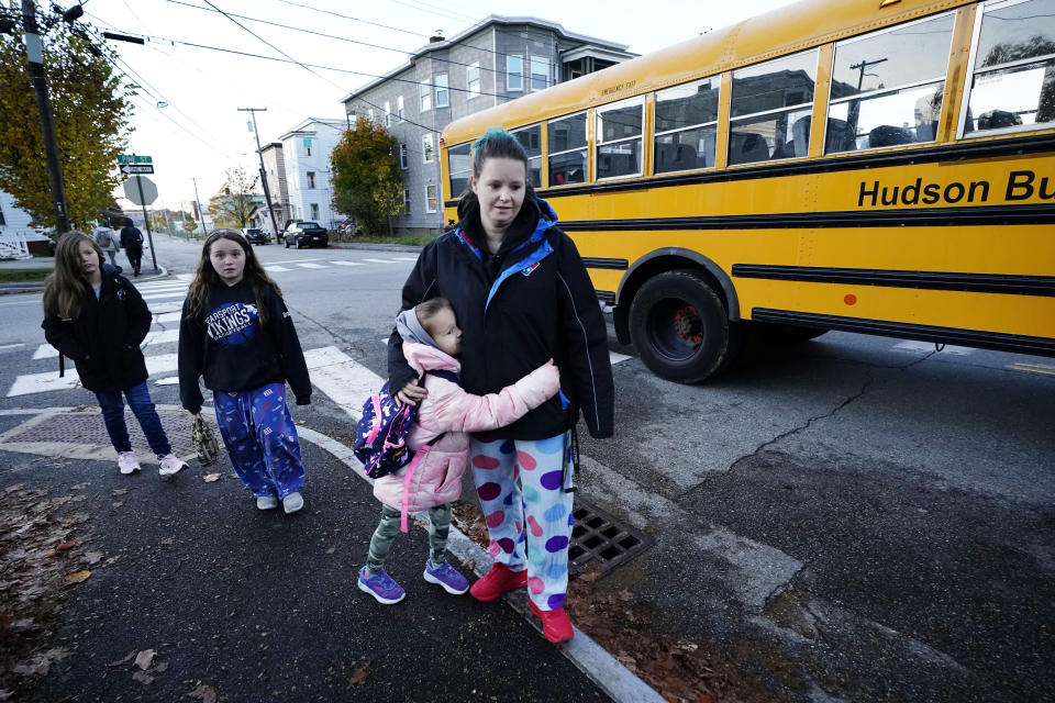 Adrienne Dyment is hugged by her daughter Paizley as the school bus arrives as classes resume in the wake of last week's mass shootings, Tuesday, Oct. 31, 2023, in Lewiston, Maine. (AP Photo/Robert F. Bukaty)