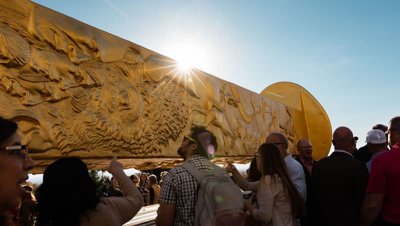 Attendees step up to see the Golden Spike Monument after its arrival in front of the Utah state Capitol in Salt Lake City on Monday, Oct. 23, 2023. The 43-foot-tall golden spike was commissioned as a public art piece by the Golden Spike Foundation to honor the tens of thousands of railroad workers who built the transcontinental railroad.