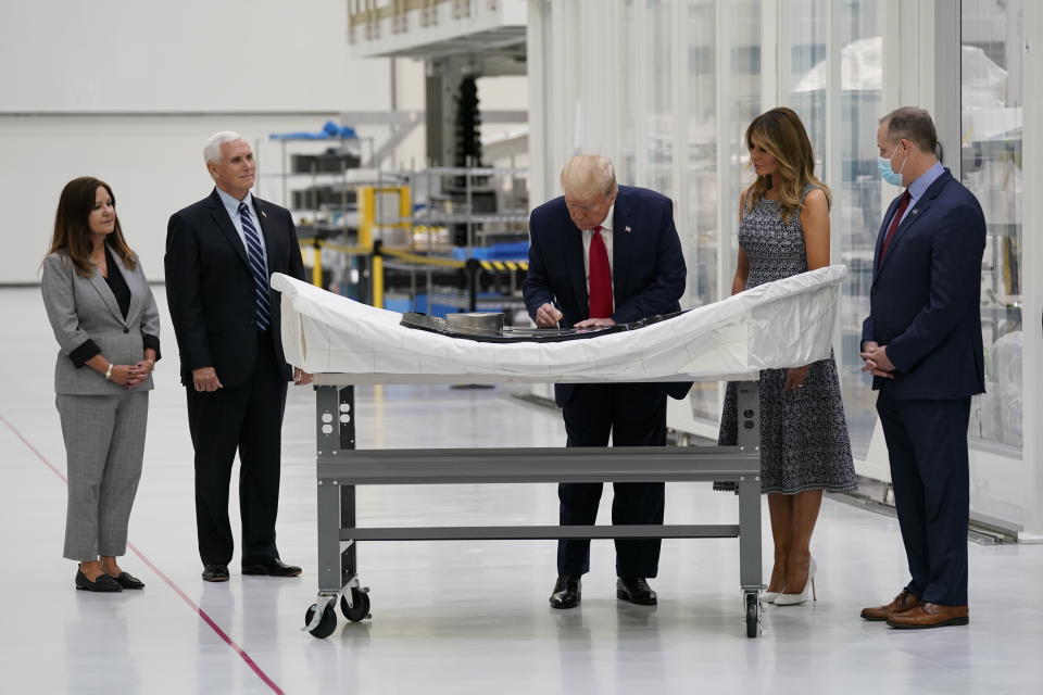 President Donald Trump signs a piece of equipment as he and first lady Melania Trump participate in a tour of NASA facilities before viewing the SpaceX Demonstration Mission 2 Launch at Kennedy Space Center, Wednesday, May 27, 2020, in Cape Canaveral, Fla. Vice President Mike Pence, second from left, second lady Karen Pence, left, and NASA Administrator Jim Bridenstine look on. (AP Photo/Evan Vucci)