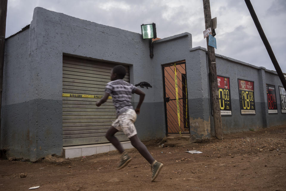 A boy runs past the tavern where the body of 5-year-old Wandi Zitho was found after he was murdered less than two weeks earlier in Orange Farm, South Africa, on April 27, 2020. The bar owner was arrested and later released because of a lack of evidence. (AP Photo/Bram Janssen)