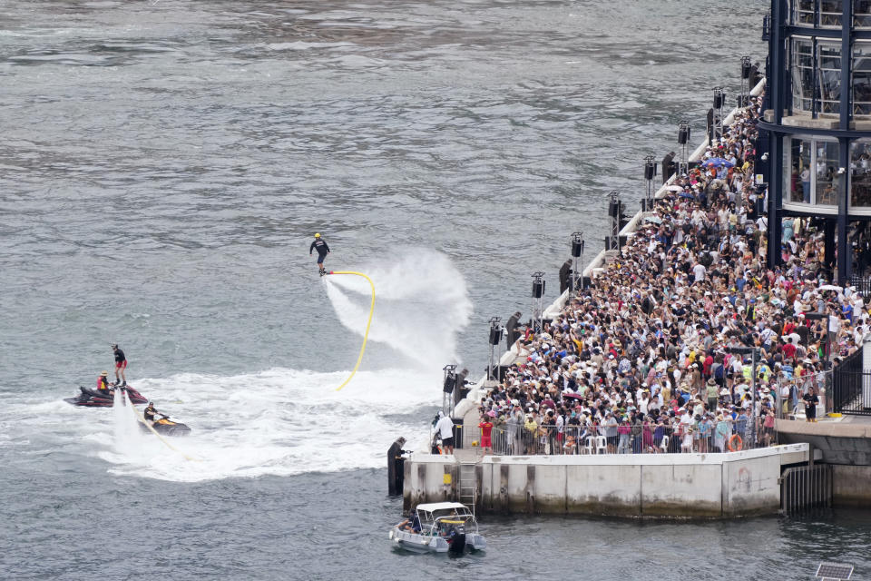 A crowd along the harbor are entertained by 2 people Flyboarding during Australia Day celebrations in Sydney, Friday, Jan. 26, 2024. (AP Photo/Rick Rycroft)