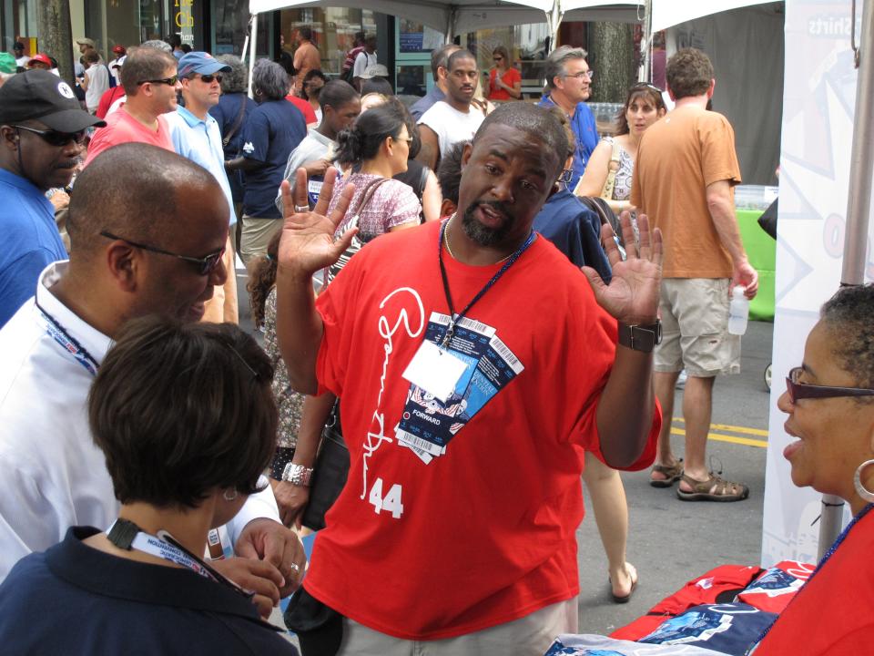Adrian Stone talks to a customer about the T-shirts he is selling during Carolina Fest in Charlotte, N.C. on Monday, Sept. 3, 2012. Stone had to spend six months getting his designs approved by the Democratic National Convention and getting permission to sell the shirts in the convention zone. (AP Photo/Jeffrey Collins)