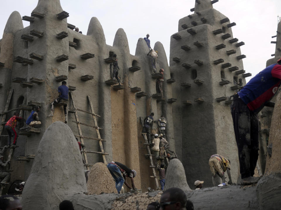 Malians take part in the annual replastering of the world's largest mud-brick building, the Great Mosque of Djenne, Mali, Sunday, May 12, 2024. The building has been on UNESCO's World Heritage in Danger list since 2016. The mosque and surrounding town are threatened by conflict. Djenne's mosque requires a new layer of mud each year before the start of the rainy season in June. (AP Photo/Moustapha Diallo)