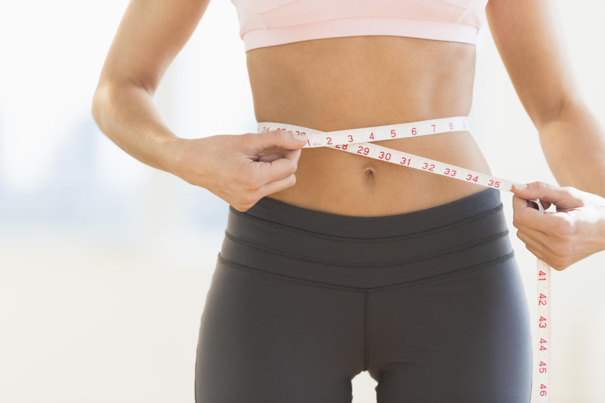 woman measuring waistline with measuring tape