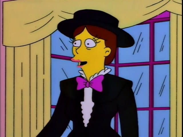 Shary Bobbins stands in the Simpsons' living room, she's wearing a broad brimmed black hat, a suit and a purple bow tie