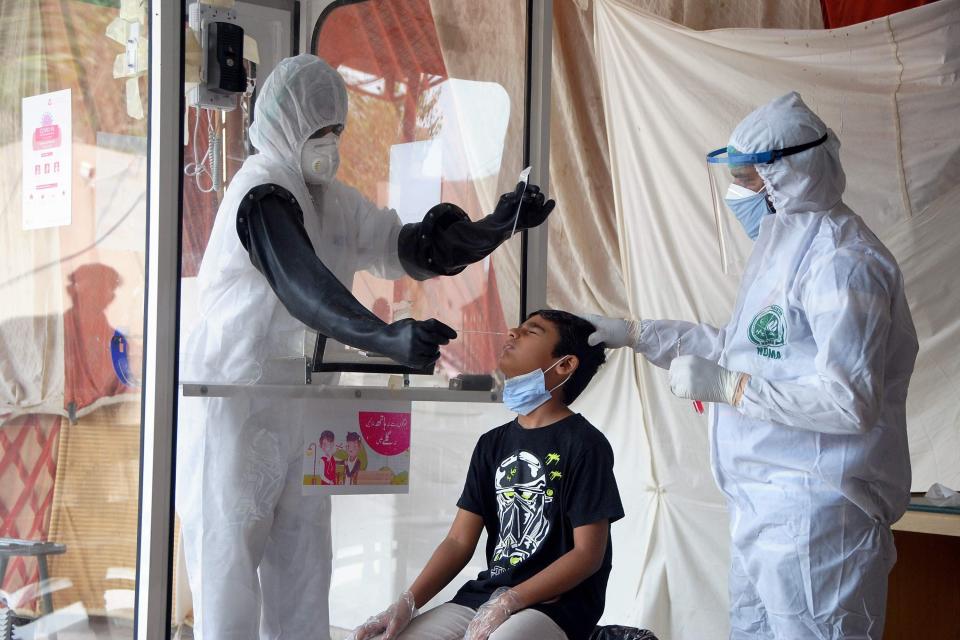 FILE - In this Friday, June 26, 2020 file photo, health workers take a nasal swab sample during a testing and screening operation for the new coronavirus, in Hyderabad, Pakistan. (AP Photo/Pervez Masih, File)