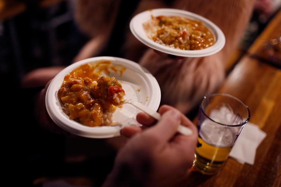 Masquerade attendees eat etouffee from Marker-7 during the 4th Annual Historic Athens Mardi Gras Masquerade and Block Party at Terrapin Brewery in Athens, Ga., on Tuesday, March 1, 2022.