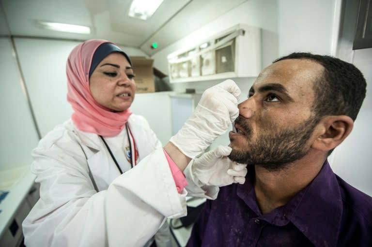 A medic takes a sample from an Egyptian labourer being tested for Hepatitis C at a construction site on August 3, 2017