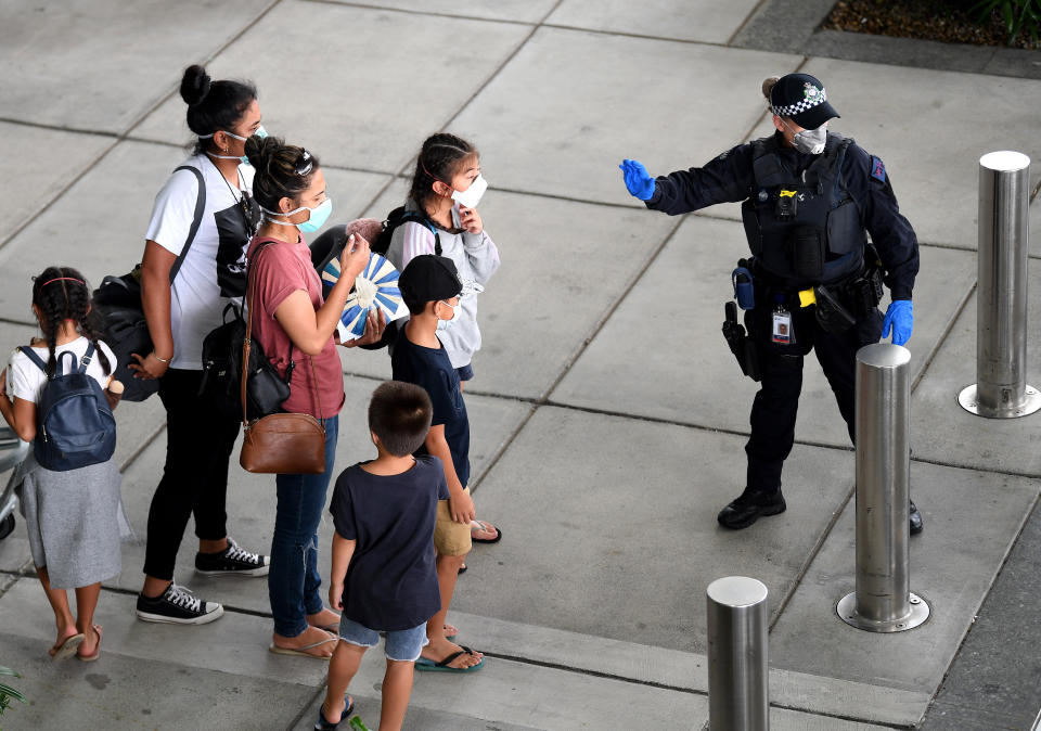 A police officer directs passengers who came on a special international repatriation flight in Brisbane. Source: AAP