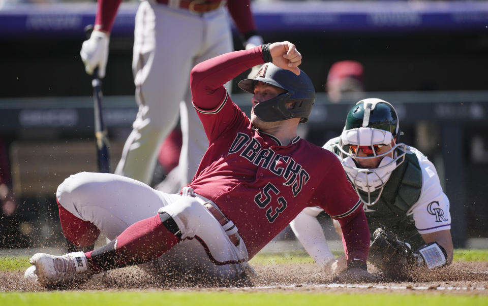 Arizona Diamondbacks' Christian Walker, left, safely steals home plate as Colorado Rockies catcher Brian Serven fields the throw in the third inning of a baseball game Sunday, Sept. 11, 2022, in Denver. (AP Photo/David Zalubowski)