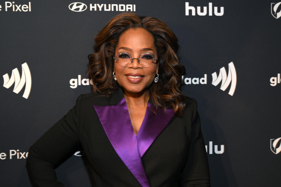 Oprah Winfrey on the GLAAD Awards red carpet, wearing a suit with a wide lapel, and glasses