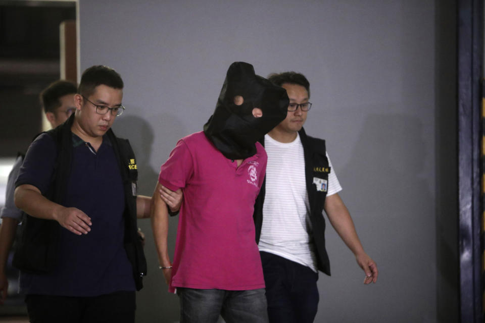 In this Monday, July 22, 2019, photo, a suspect is escorted by Hong Kong policemen in relation to a Sunday mob attack at a subway station in Hong Kong. Hong Kong is reeling after a large gang of men in white shirts brutally beat dozens of people inside a train station in a shocking new twist to the city's summer of protest. Six men have been detained, some with gang links, police said, without elaborating. The sudden attack, which came as a massive protest was winding down Sunday night, has spurred speculation about the men's backgrounds, motivations and possible political ties. (AP Photo)
