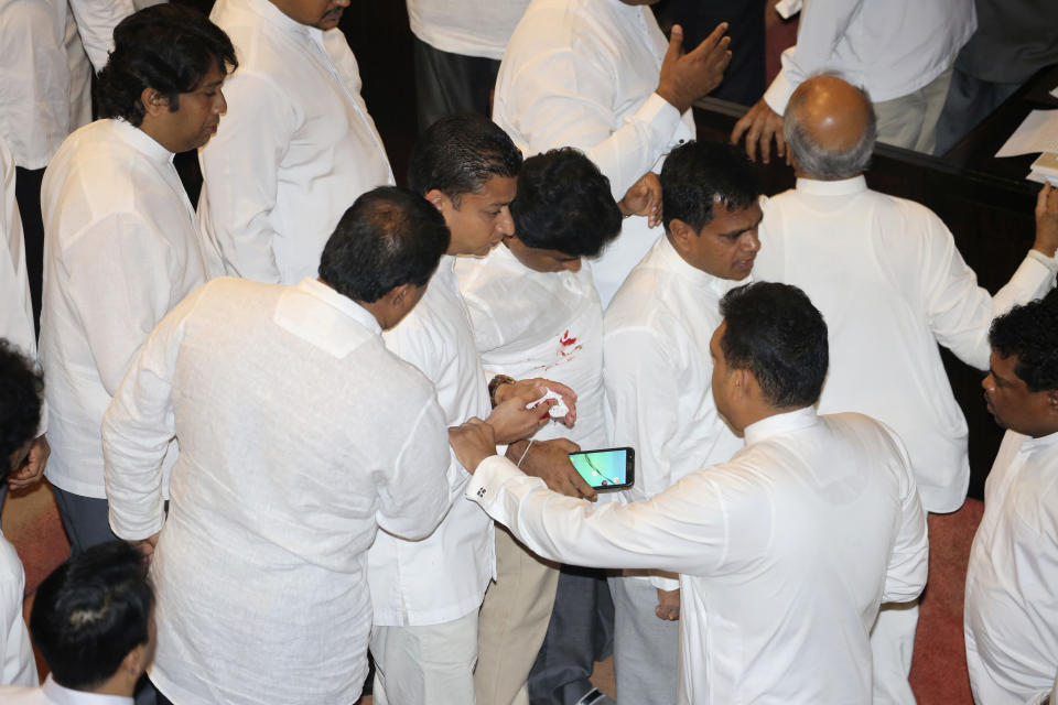 Sri Lankan Lawmaker Dilum Amunugama is helped by colleagues after he sustained an injury during a fight in the parliament chamber in Colombo, Sri Lanka, Thursday, Nov. 15, 2018. Rival lawmakers exchanged blows in Sri Lanka's Parliament on Thursday as disputed Prime Minister Mahinda Rajapaksa claimed the speaker had no authority to remove him from office by voice vote. (AP Photo/Lahiru Harshana)