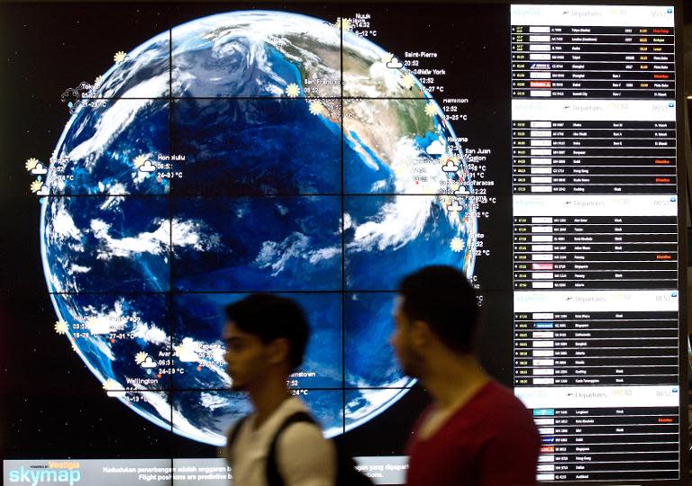 Passengers walk past an information screen on July 18, 2014 at the Kuala Lumpur International Airport in Sepang