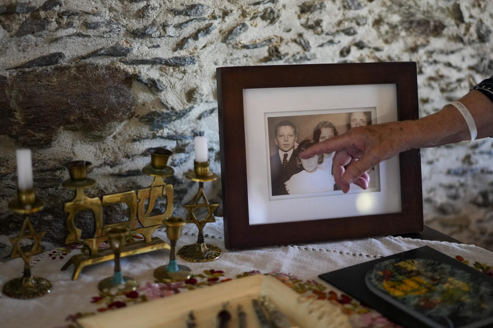 Rabbi Barbara Aiello points at her younger self in an old family photo, in her "Ner Tamid del Sud" (The Eternal Light of the South) synagogue in Serrastretta, southern Italy, Friday, July 8, 2022. From a rustic, tiny synagogue she fashioned from her family's ancestral home in this mountain village, American rabbi Aiello is keeping a promise made to her Italian-born father: to reconnect people in this southern region of Calabria to their Jewish roots, links nearly severed five centuries ago when the Inquisition forced Jews to convert to Christianity. (AP Photo/Andrew Medichini)