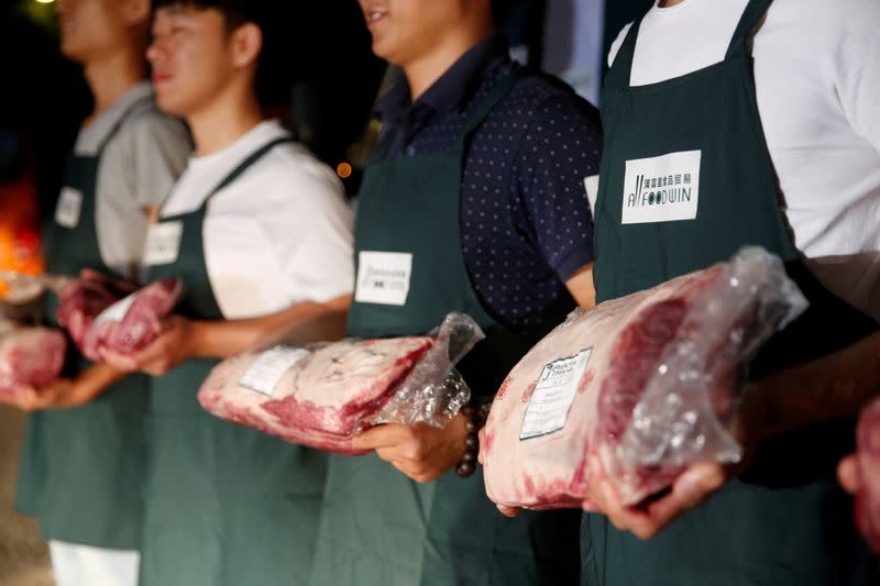 FILE PHOTO: Employees of Shanghai All Food Win Co., Ltd. pose with beef at a storage area near the Pudong International Airport in Shanghai