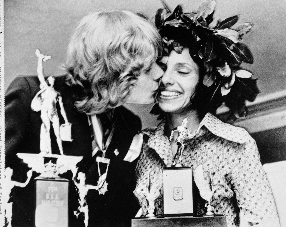 FILE - Olavi Suomalainen of Finland, winner of the men's division of the Boston A.A. Marathon April 17, 1972, kisses Nina Kuscsik of Long Island, N.Y., winner of the women's division, at the trophy presentation April 18, 1972. As the 2022 Boston Marathon celebrates the 50th anniversary of the first official women’s race, the occasion will be marked by one of the strongest women’s fields ever. (AP Photo/File)