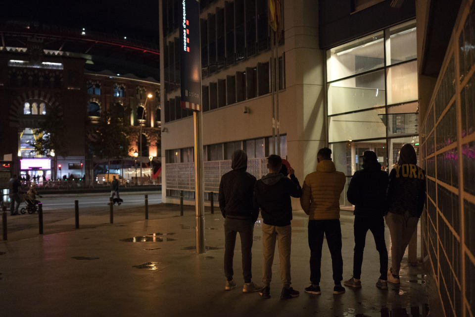 In this Nov. 9, 2018 photo, unaccompanied minors from Morocco seeking shelter, stand outside a police station in Barcelona, Spain. Slouched on a bench at a Barcelona police station, five teenagers waited patiently on a recent Friday evening to find out where they would sleep that night: a shelter for young migrants or on that bench. (AP Photo/Renata Brito)