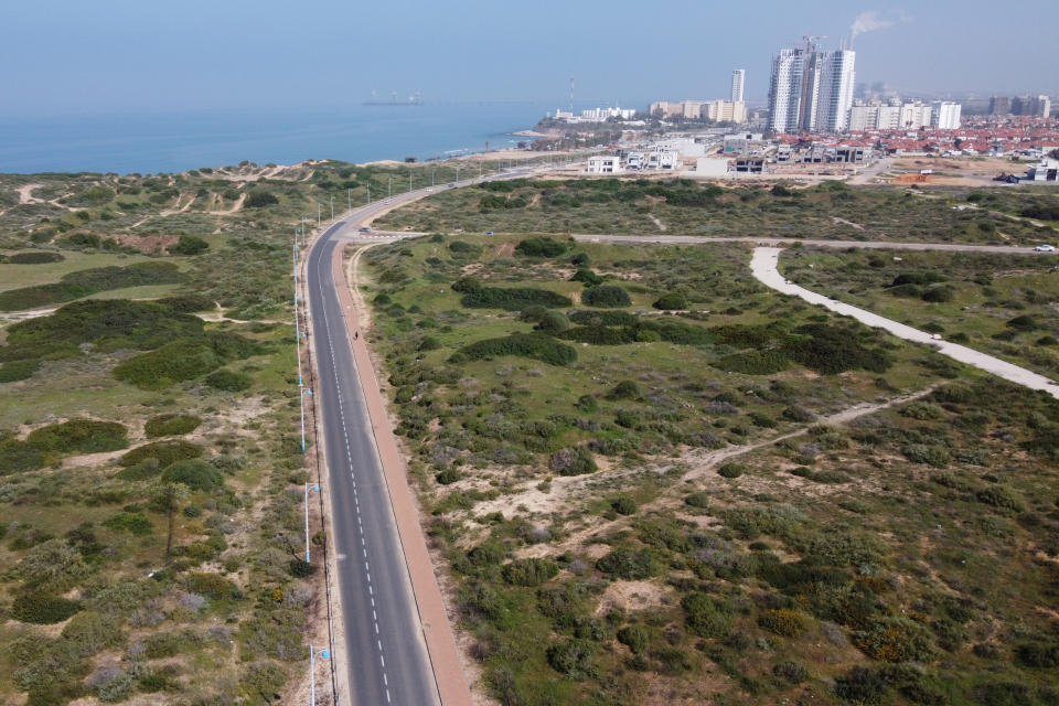 A person walks through an empty avenue in Hadera, Israel, Monday, March 16, 2020. ‏Netanyahu's Cabinet on Sunday authorized the Shin Bet security agency to use its phone-snooping tactics on coronavirus patients, an official confirmed, despite concerns from civil-liberties advocates that the practice would raise serious privacy issues. The official spoke on condition of anonymity pending an official announcement. For most people, the new coronavirus causes only mild or moderate symptoms. For some it can cause more severe illness. (AP Photo/Ariel Schalit)