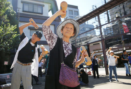 Elderly and middle-aged people exercise with wooden dumbbells during a health promotion event to mark Japan's "Respect for the Aged Day" at a temple in Tokyo's Sugamo district, an area popular among the Japanese elderly, Japan, September 18, 2017. REUTERS/Toru Hanai