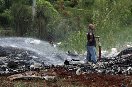 A rescue team member looks on while working in the wreckage of a Boeing 737 plane that crashed in the agricultural area of Boyeros, around 20 km (12 miles) south of Havana, on Friday shortly after taking off from Havana's main airport in Cuba, May 18, 2018. REUTERS/Alexandre Meneghini