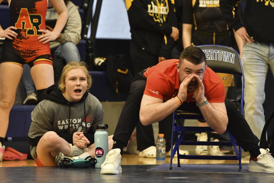 Easton Area High School wrestler Aubre Krazer, left, and girls wrestling coach Jordan Kutler, right, cheer one of the school's wrestlers during the Southeast Regional wrestling tournament Sunday, Feb. 25, 2024, in Quakertown, Pa. Girls’ wrestling has become the fastest-growing high school sport in the country. (AP Photo/Marc Levy)
