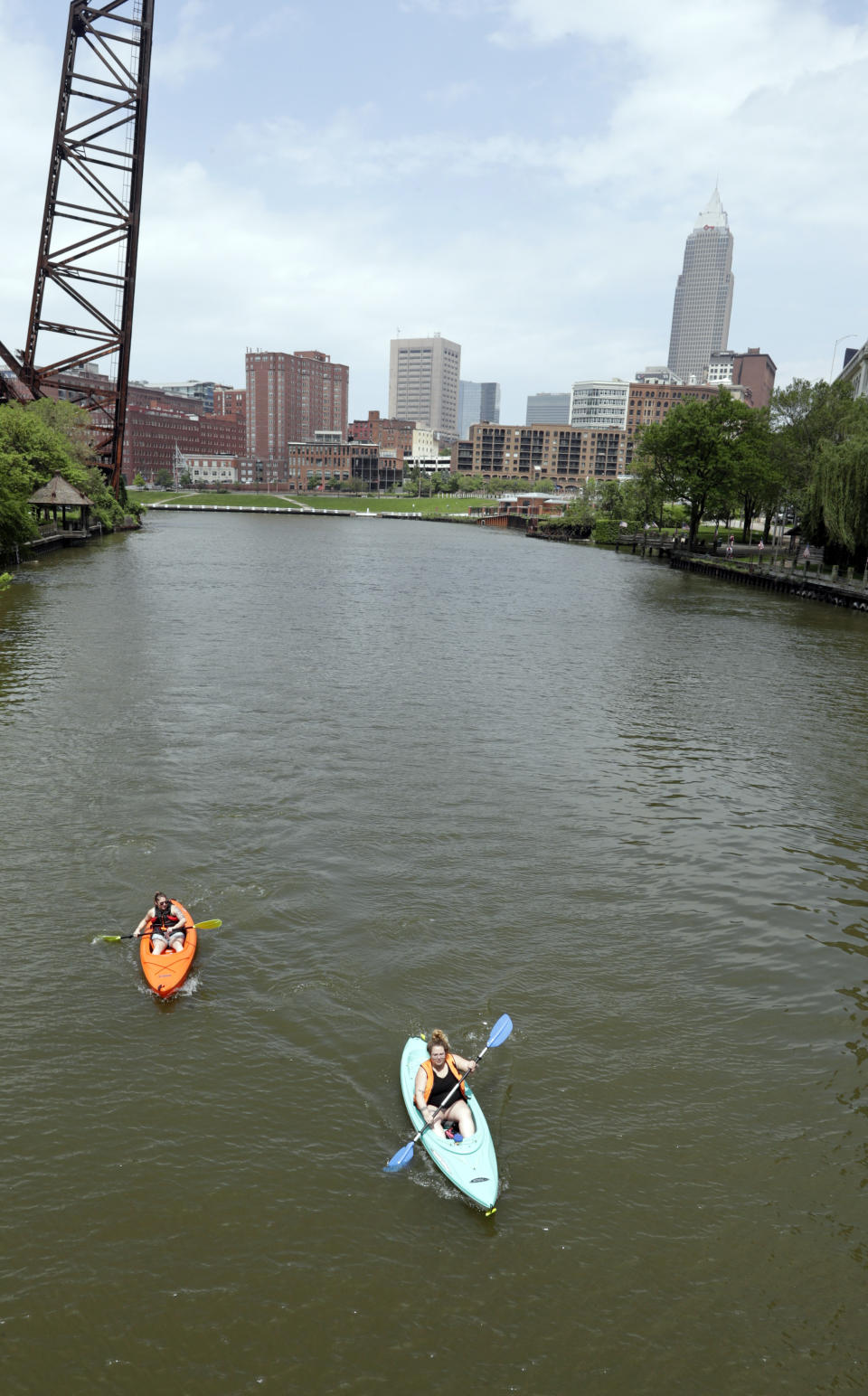 Kylie Augustine, left, and Ashlie Prosky paddle in kayaks on the Cuyahoga River, Tuesday, May 28, 2019, in Cleveland. Fifty years after the Cuyahoga River's famous fire, a plucky new generation of Cleveland artists and entrepreneurs has turned the old jokes about the “mistake on the lake” into inspiration and forged the decades of embarrassment into a fiery brand of local pride. (AP Photo/Tony Dejak)