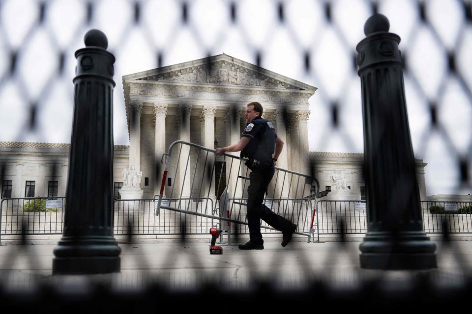 A police officer carries a barricade May 5. Fences have been set up around the Supreme Court in response to the protests that erupted over a leaked draft of a court decision against abortion.