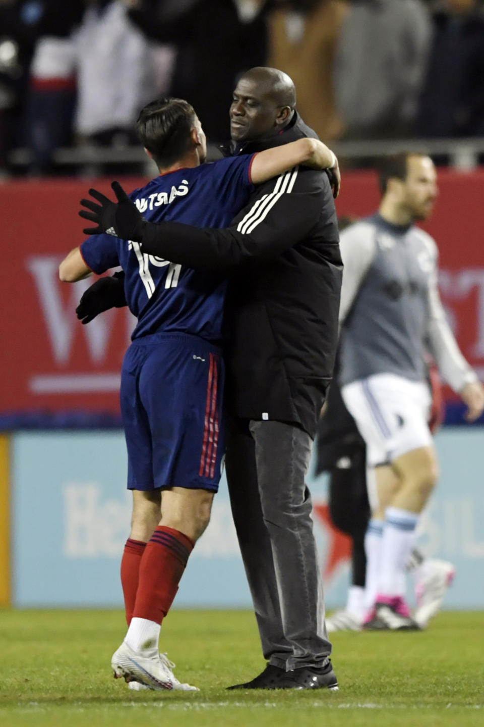 Chicago Fire head coach Ezra Hendrickson right, hugs George Koutsias (19) after defeating Minnesota United 2-1 in an MLS soccer game Saturday, April 8, 2023 in Chicago. This was Koutsias' first MLS game after being called up from Greece. (AP Photo/Paul Beaty)