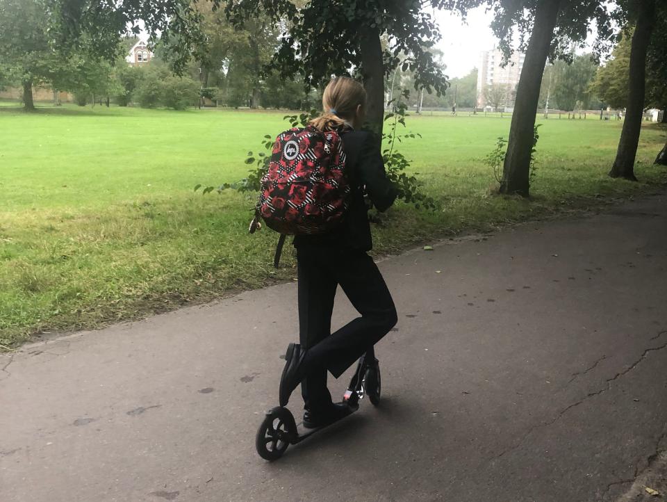 Kid riding a scooter wearing a school uniform