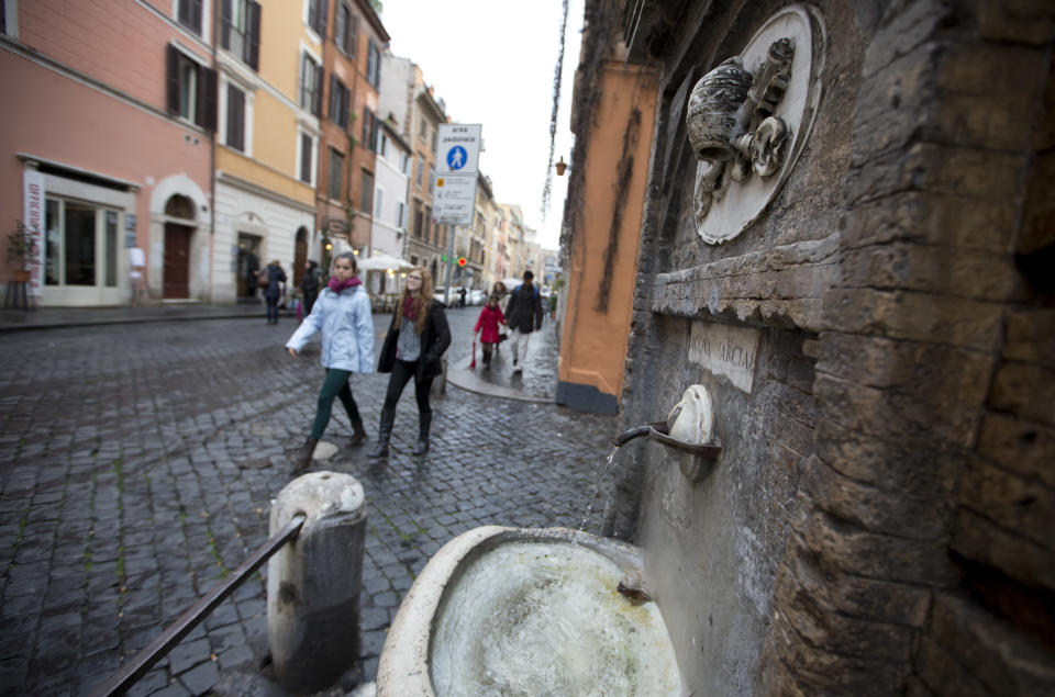 People walk past a fountain in Borgo Pio, near the Vatican, in Rome, Monday, March 18, 2013. Borgo, the sleepy, medieval neighborhood with a timeless feel right outside the Vatican's borders, has been at the service of pontiffs for centuries. From resoling to risotto, from light bulbs to linguine, Borgo is the go-to place for up-and-coming cardinals and sometimes even for popes. (AP Photo/Andrew Medichini)